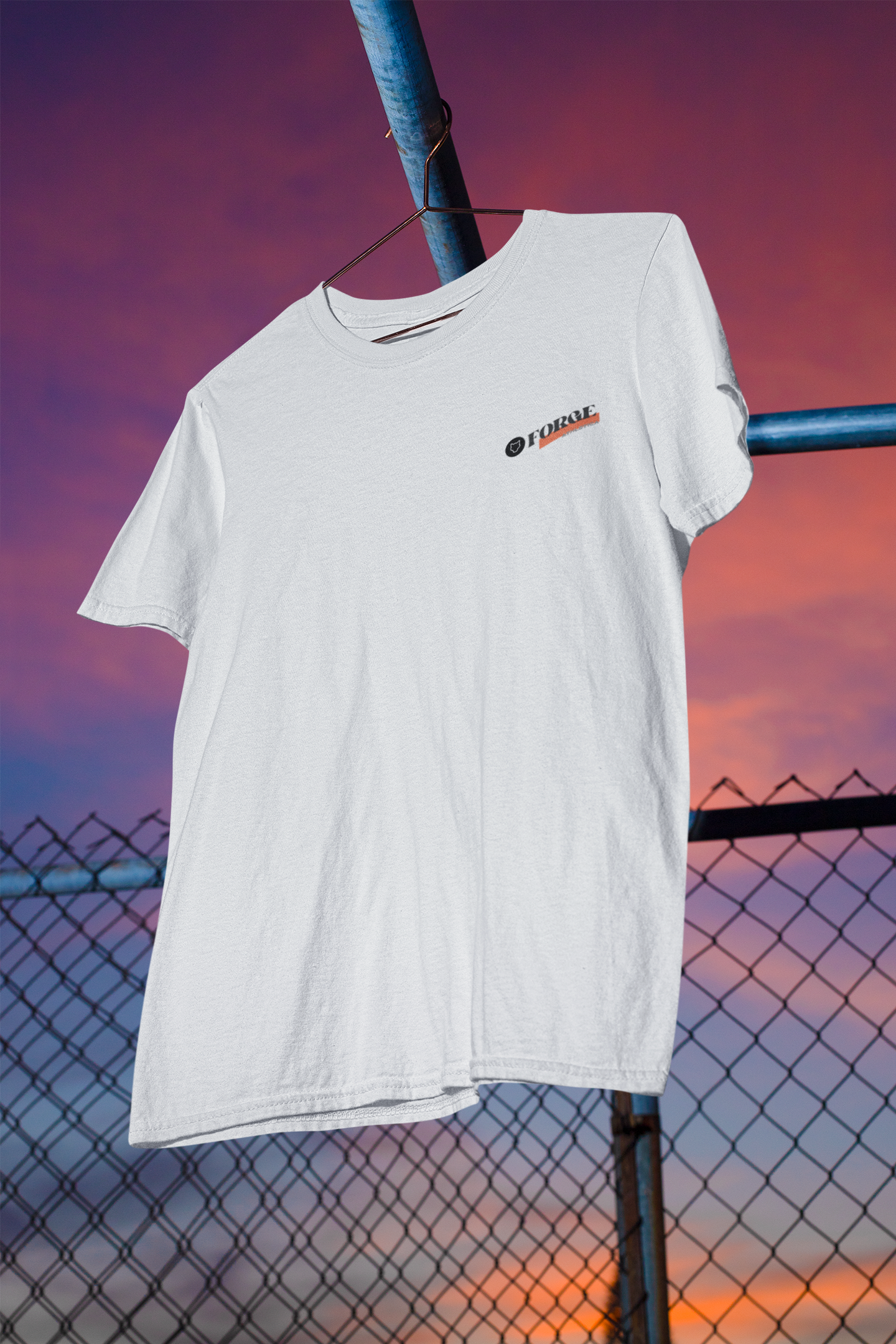 Front view of a hanging Cream Unisex Round Neck T-Shirt on a hanger with a metal fence in the background.