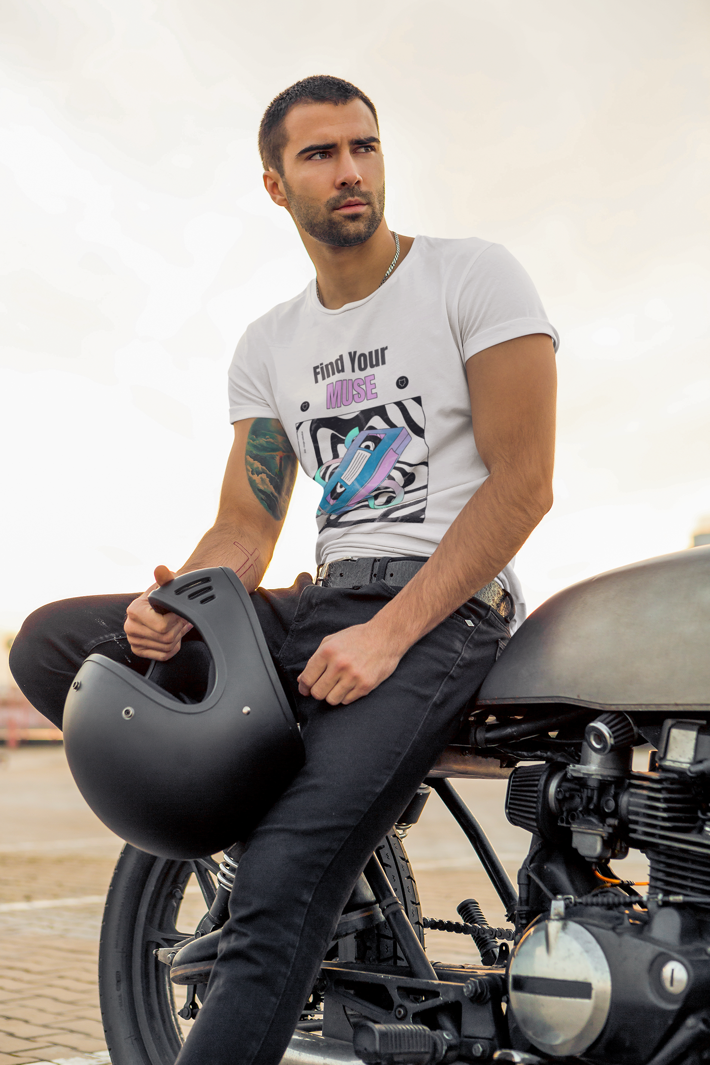 Handsome man posing in a Cream Vibrant Round Neck T-Shirt on a motorcycle with a black helmet in one hand and wearing a black denim.