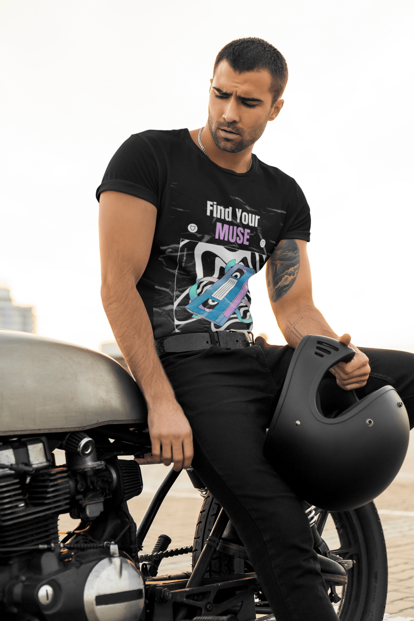 Handsome man posing in a Black Vibrant Round Neck T-Shirt on a motorcycle with a black helmet in one hand and wearing a black denim.